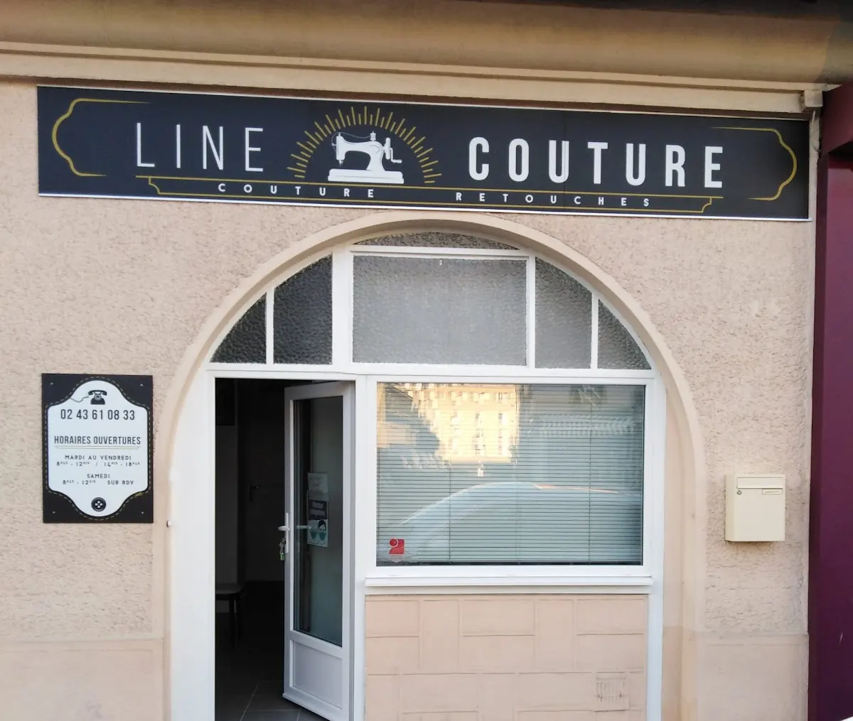 La devanture de Line Couture : l'enseigne ardoise et or au-dessus de la porte en arc, la carte des horaires à gauche.